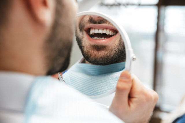 man looking at his new smile in the dental chair